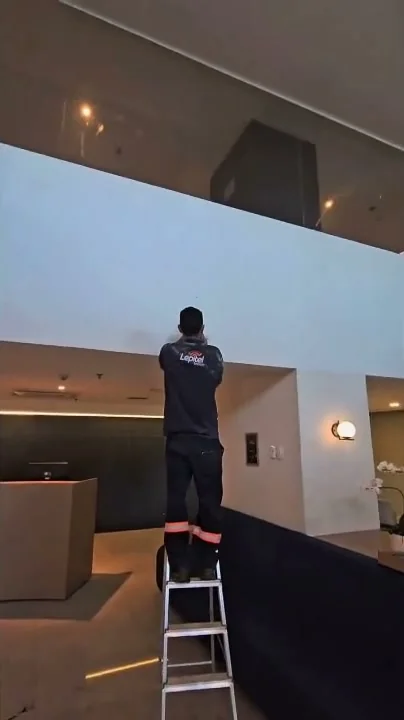 Técnico da Lepitel em escada, instalando ponto de acesso Wi-Fi 6 no forro do lobby do hotel.