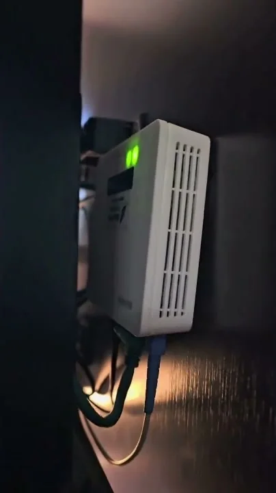 ONU branca fixada na parede de um quarto do hotel, com a fibra óptica chegando pela base.